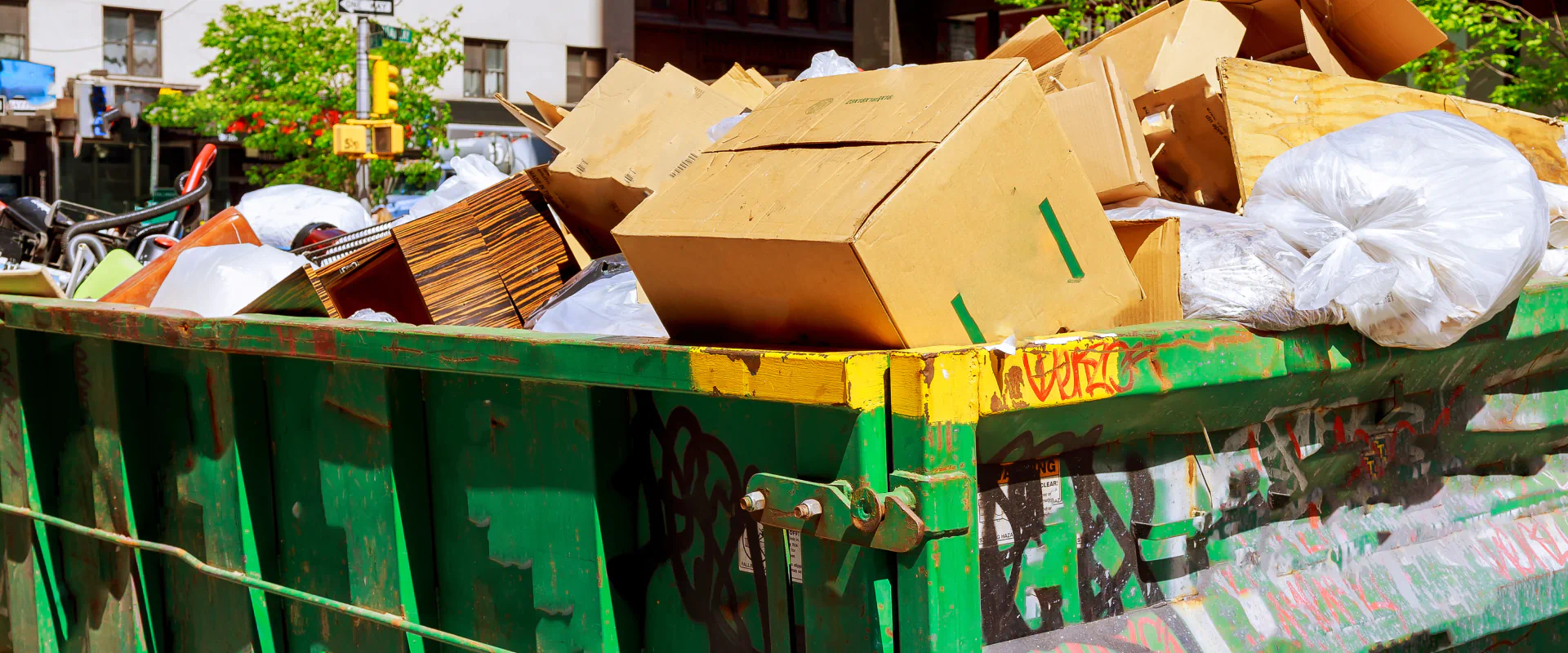 green dumpster with some cardboard boxes on it